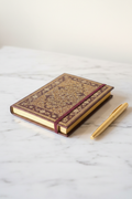 Burgundy gold filigree gilded journal cover on marble desk