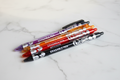 4 floral erasable retractable gel pens in purple, orange, red and black on marble desk
