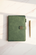 Forest green faux leather journal with antique gold clasp on marble desk