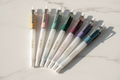 6 Starry Sky erasable glitter gel pens in pink, mauve, blue, brown, green and yellow on marble desk